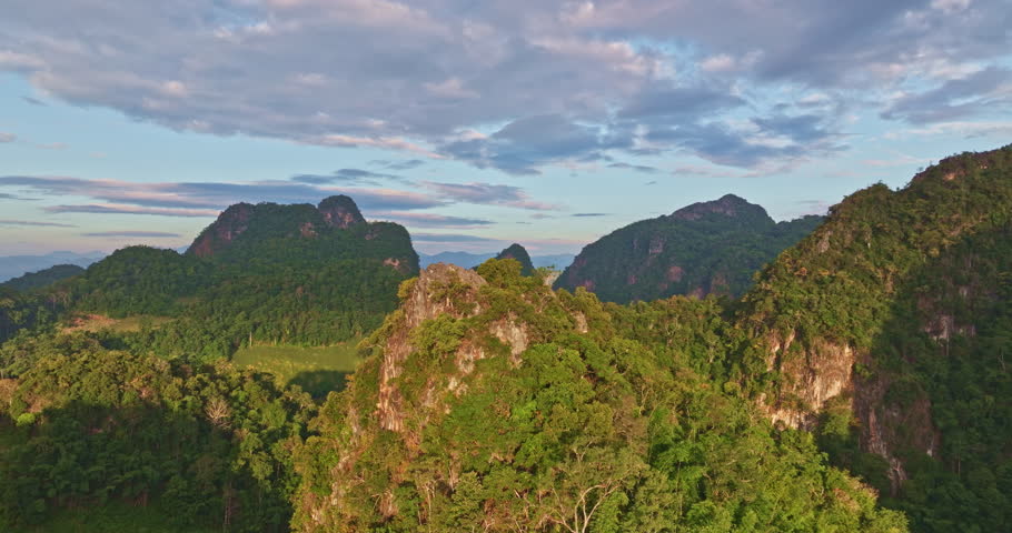 A breathtaking aerial view of a mountain village bathed in early sunlight, with misty valleys and dramatic peaks in the background. The scene captures the serene beauty of nature and the tranquility o