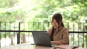Adult Asian woman enjoys outdoor remote work celebrating success. She uses a laptop for digital tasks feeling triumph and joy in her modern freelance career lifestyle. - Powered by Shutterstock - Get 15% off with code: PIKWIZARD15