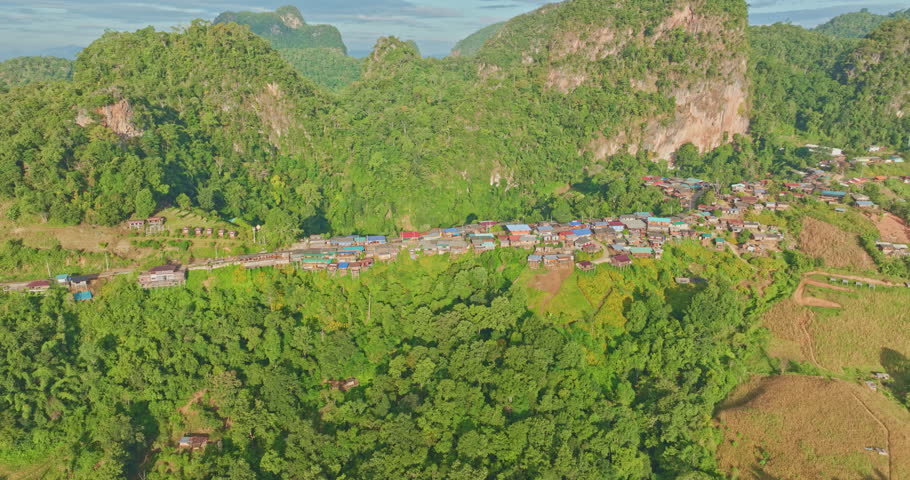 A breathtaking aerial view of a mountain village bathed in early sunlight, with misty valleys and dramatic peaks in the background. The scene captures the serene beauty of nature and the tranquility o