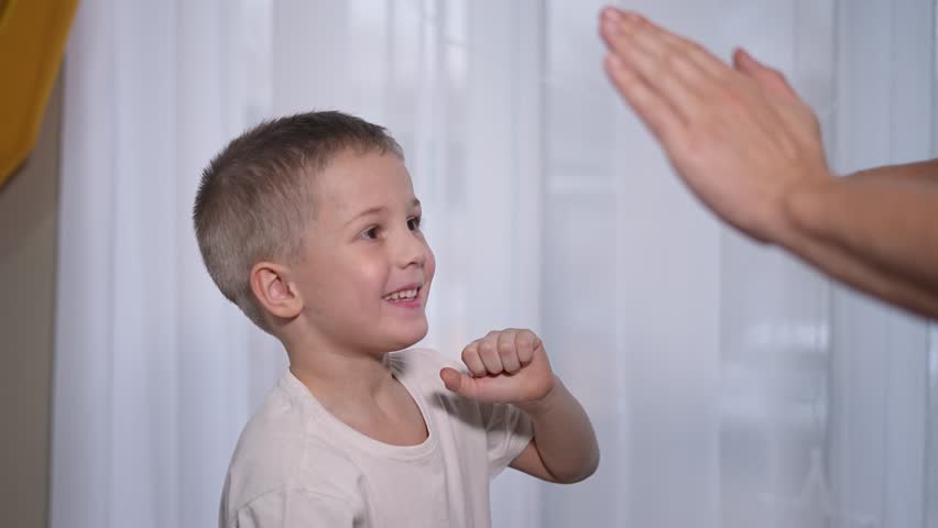 Boy in punching stance near coach. Child practicing martial motion in training. Learning self-discipline through exercise. Punching improves fitness. Boy repeats move for martial skill development