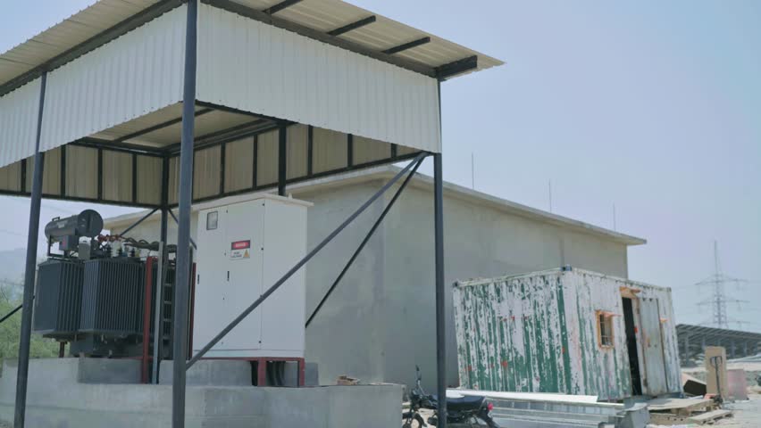 Profile view of a electrical transformer beneath a shed.