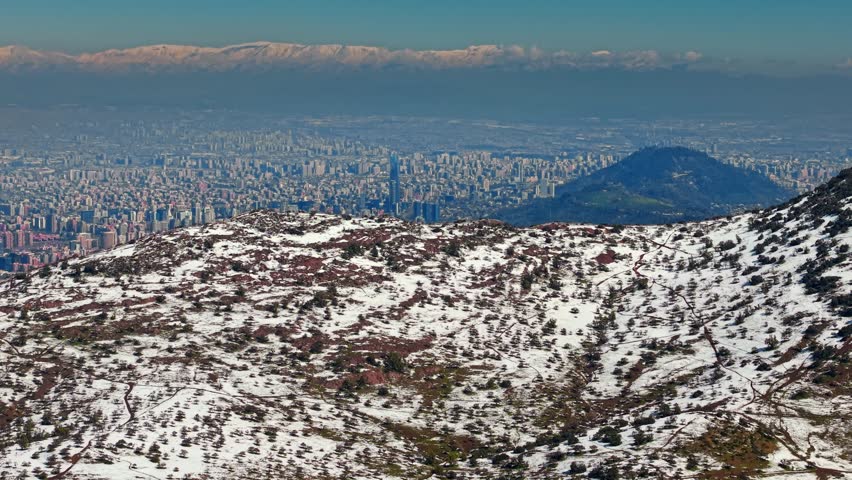 Upward pedestal shot revealing snowy hills in Santiago, Chile, with the skyline visible in the background.