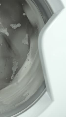 Washing machine washes white clothing and sheets. Cylinder spinning. Nobody. Vertical footage