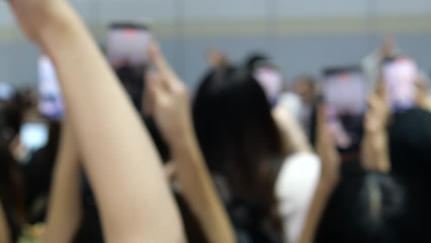 Teenage fans using mobile phones to take videos and photos of celebrity