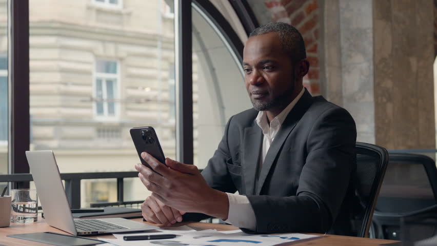 Happy business winning with phone African American businessman mobile win man in office online achievement victory middle aged manager executive excited winner male with smartphone app betting triumph
