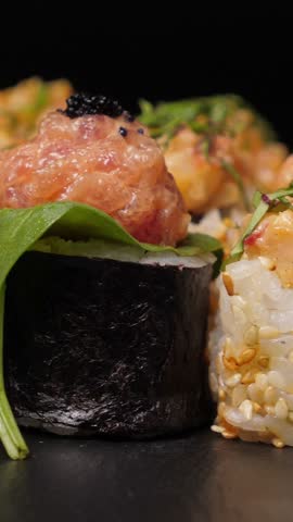 Sushi roll baked eel on black slate plate. Rotate. Vertical footage