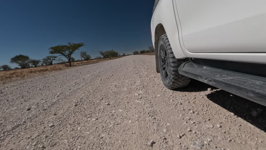 Close-up of a car wheel driving on a gravel road in Africa.