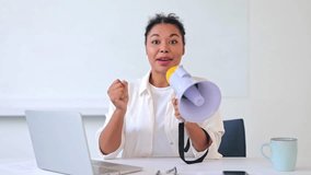 Excited dark-skinned businesswoman, dressed in a white shirt, confidently uses a megaphone to convey an important announcement in a bright office. Feelings of enthusiasm and communication. - Powered by Shutterstock - Get 15% off with code: PIKWIZARD15