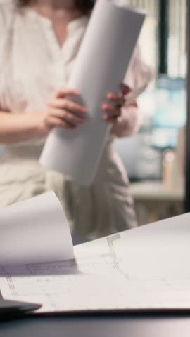Vertical Video Real estate developer reviews master plan with construction layouts on laptop, ensuring the residential project aligns with market trends, zoning regulations and urban landscape. Camera
