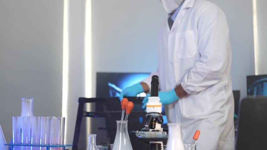 A male scientist in a lab holds up a flask with red liquid. He is looking at the results of a chemical test as part of an important research project for new medicine. - Powered by Shutterstock - Get 15% off with code: PIKWIZARD15