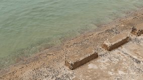 High angle view of a weathered concrete seawall with steps leading into the calm, murky green water of the sea. - Powered by Shutterstock - Get 15% off with code: PIKWIZARD15
