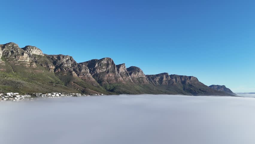 Aerial footage of table mountain in Cape Town, South Africa, surrounded by mist and clouds with only the peak emerging above the fog