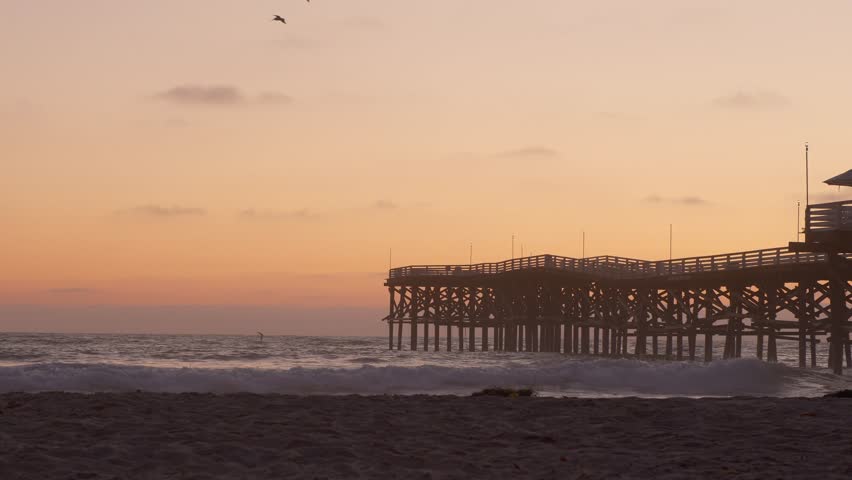 beautiful orange yellow golden hour sunset over pacific beach san diego california with crystal pier dock, southern california summer
