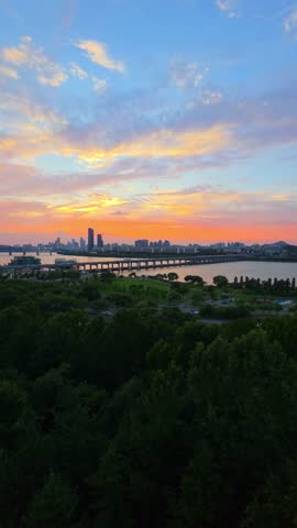 Colorful clouds above Seoul skyline during sunset, panning from Banpo Bridge to Namsan Tower with lush Hangang Park