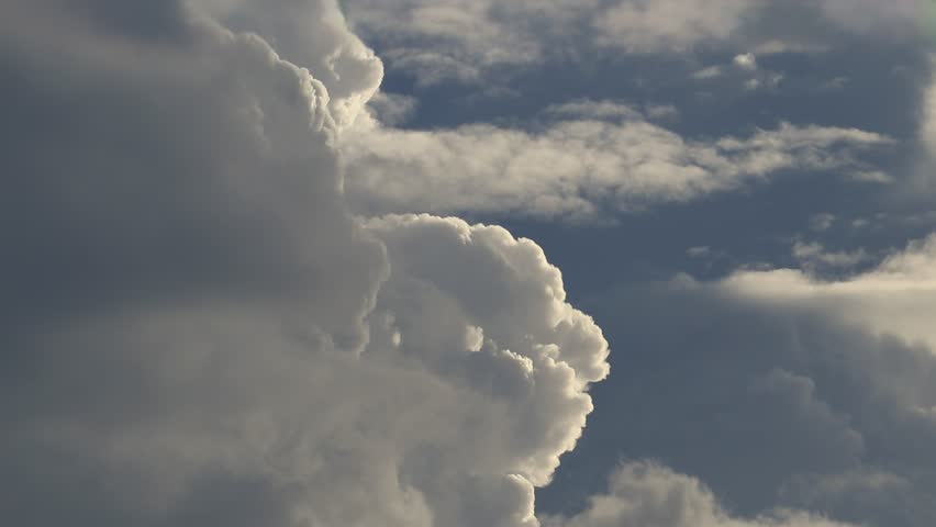 A dramatic time-lapse or slow motion video of powerful storm clouds backlit by the sun, creating a beautiful silver lining effect on their edges.