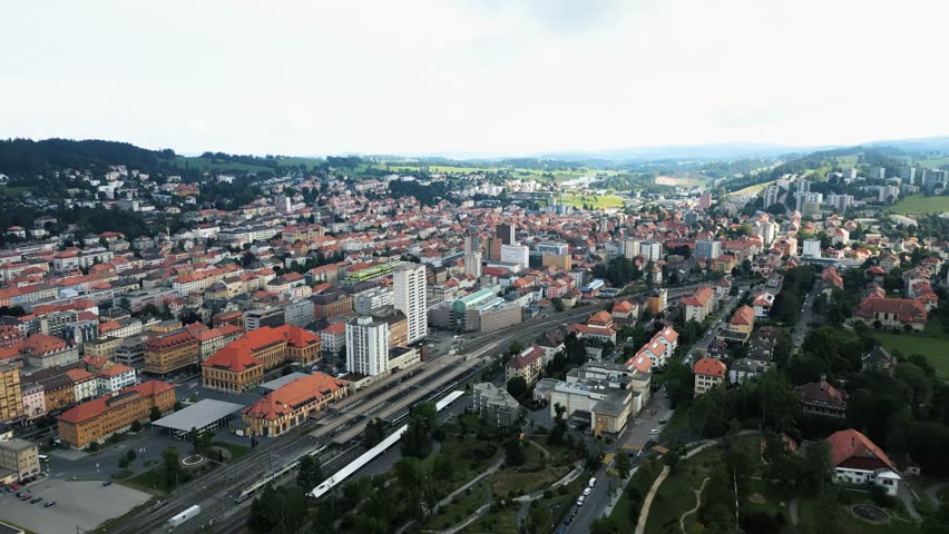 Aerial view of the city of La Chaux-de-Fonds showcasing the urban layout with buildings, train tracks and surrounding green hills, La Chaux-de-Fonds, Neuchâtel, Switzerland.
