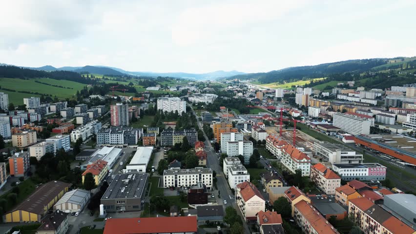 Aerial view of buildings and trainyard amidst rolling hills, an urban landscape contrasting the natural beauty, La Chaux-de-Fonds, Neuchâtel, Switzerland.