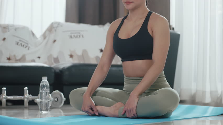 Attractive Asian woman in sportswear exercising at home.