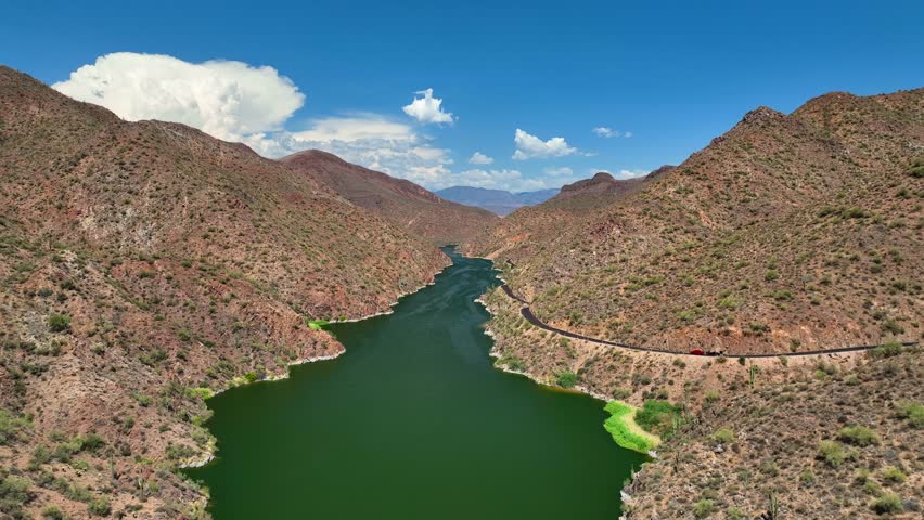 Aerial view of Theodore Roosevelt Lake winding through rugged mountains, a stark contrast to the vibrant green water, Theodore Roosevelt lake, Arizona, United States.