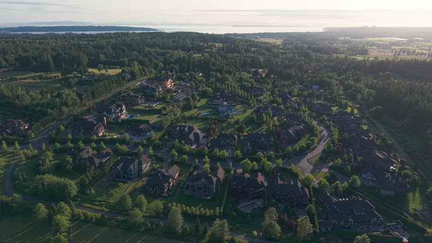 Luxury homes in Langley Township in British Columbia Canada surrounded by green lush trees under a clear blue sky