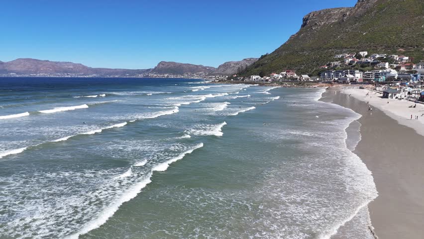 Drone flying just above the Atlantic Ocean waves with Cape Town visible in the distance, capturing the coastline and cityscape South Africa travel destination