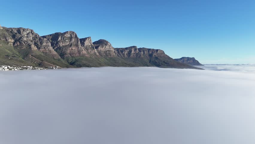 drone fly above sea of clouds with mountains emerging from fog in Cape Town South Africa