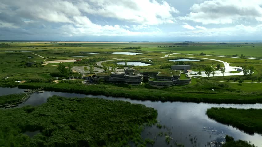 High-angle drone shows green-roof centre with roads, paths, wetlands