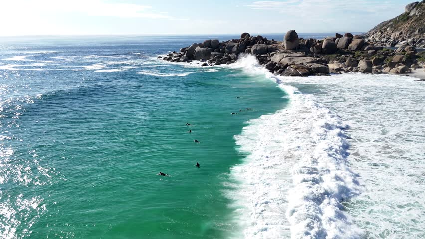 aerial view of surfers waiting for the perfect waves in Atlantic Ocean coastline of Cape Town in South Africa