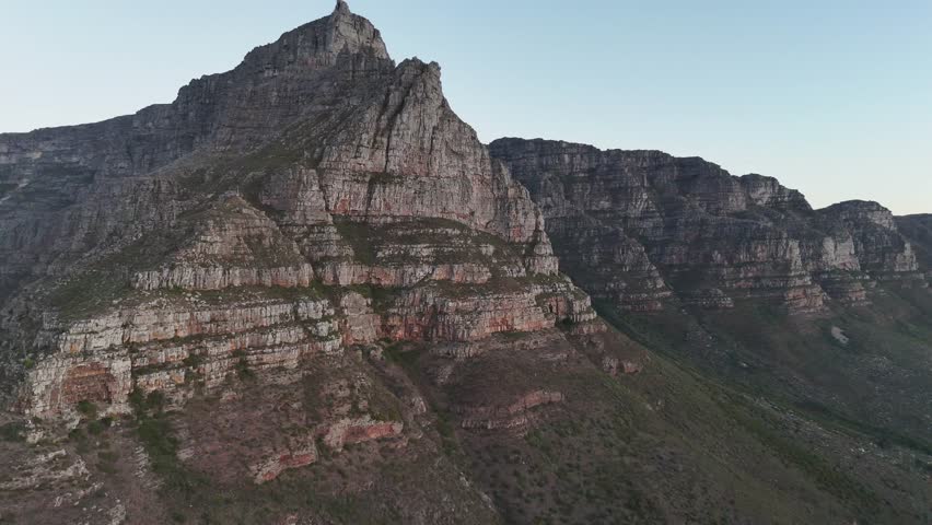 Sunset aerial shot of Table Mountain, Cape Town, South Africa, highlighting rugged cliffs, golden light