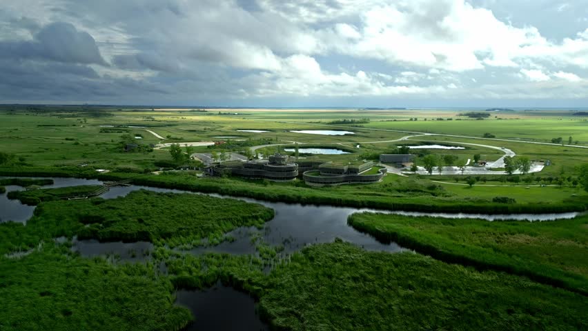 Sunbeams break through clouds over eco centre amid summer marshland