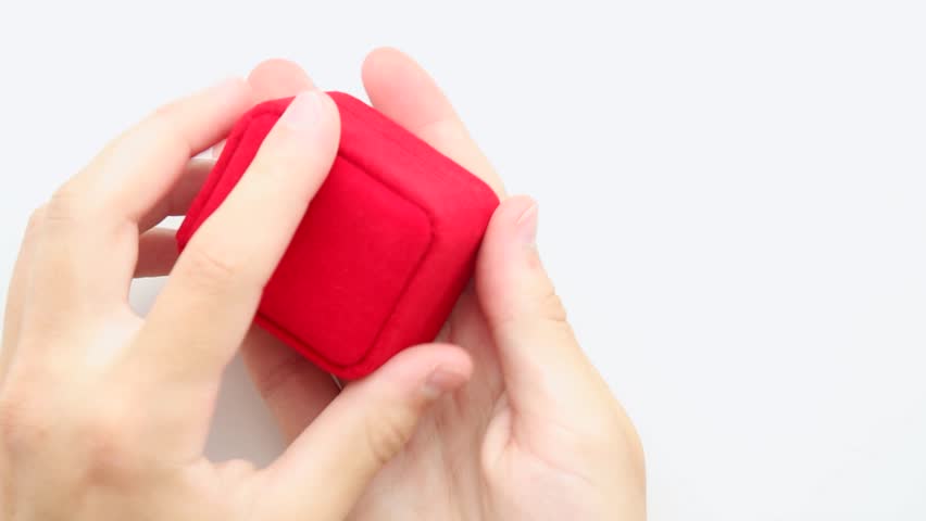 Hands opening red proposal ring box creating magical surprise moment revealing beautiful engagement ring for romantic occasion