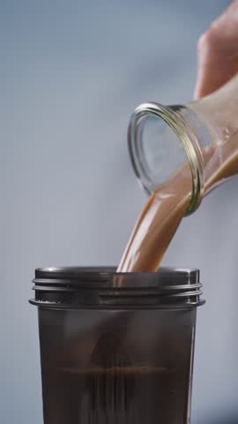 protein drink pouring into pink plastic cup. whey sports nutrition. dry mixture for preparation of sporting or dietary drink.