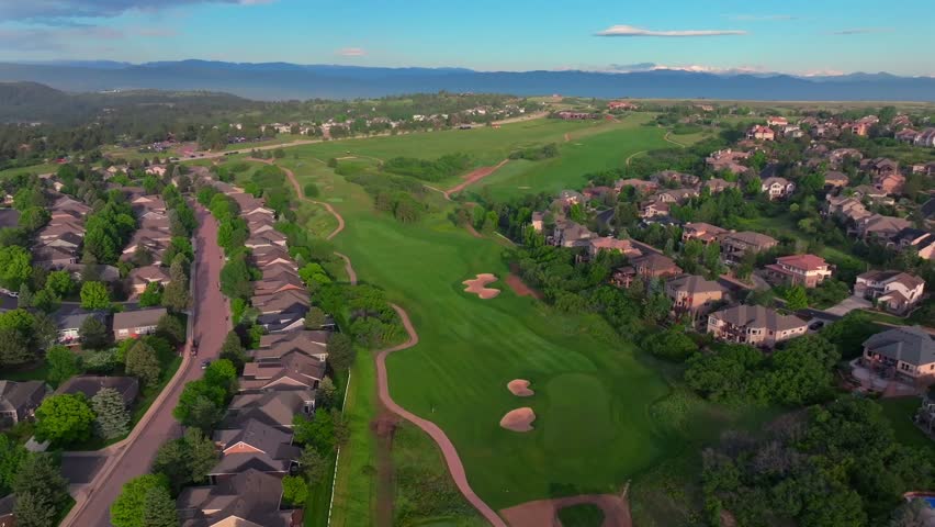 The Ridge North Castle Pines Village Golf Course aerial drone Colorado summer golfing front range neighborhood homes spring lush green grass fairway sand traps morning blue sky sunrise backwards