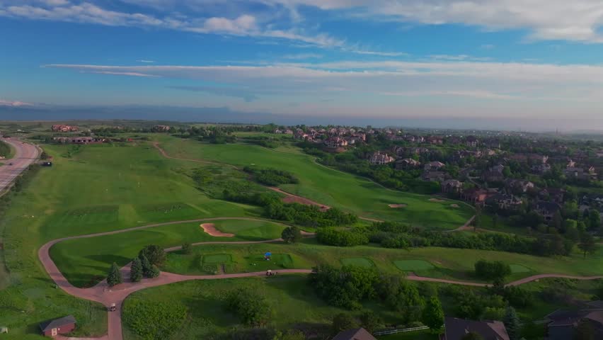 Summer driving range The Ridge North Castle Pines Village Golf Course aerial drone Colorado front range neighborhood homes spring green lush early morning sunrise golden hour forward pan up motion