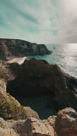 A view of Rugged cliffs of western Portugal meet the Atlantic, waves crashing against dramatic rocky shores