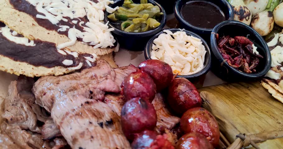 Detail shot of Oaxacan dishes, showcasing sausages, vegetables, edible insects, legumes, tamales, and mole, representing the diversity of this UNESCO Intangible Cultural Heritage