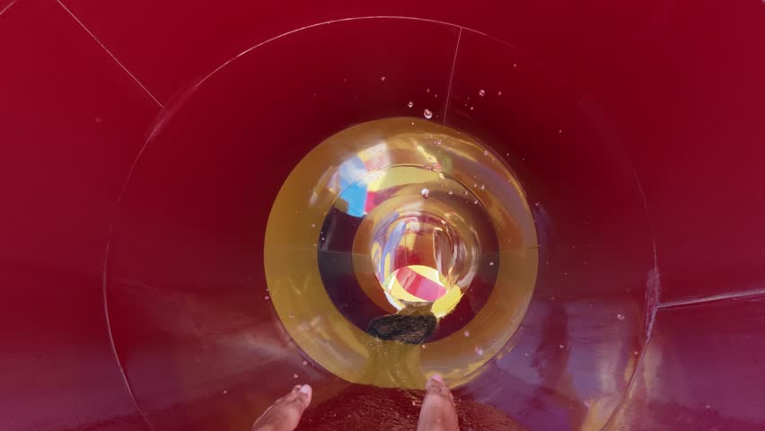POV video of person sliding into colorful funnel on a water slide, splashing water and bright striped walls, summer fun at aquapark