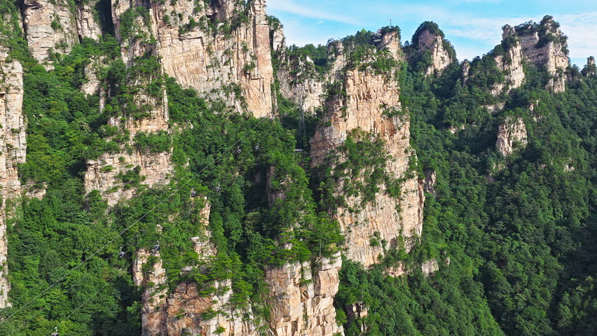 Aerial shot of the cable car through the spectacular quartz-sandstone pillars and lush green forest. Famous Zhangjiajie national forest park in Hunan, China.