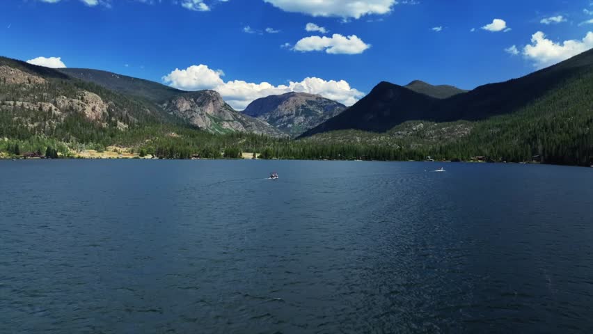 Summer Grand Lake Granby pontoon boating sailboat aerial drone Colorado Rocky Mountains National Park entrance sunny morning daytime clouds lake homes blue sky sunny clouds forward upwards motion