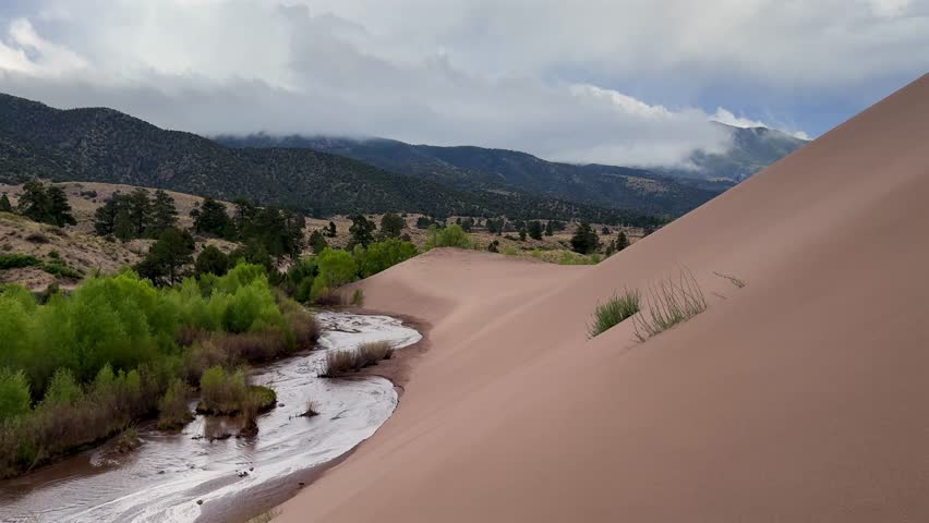 Medano Creek river landscape Great Sand Dunes National Park Sangre de Cristo range Rocky Mountains spring summer raining cloudy Colorado unique magical large amounts of sand dune hills windy