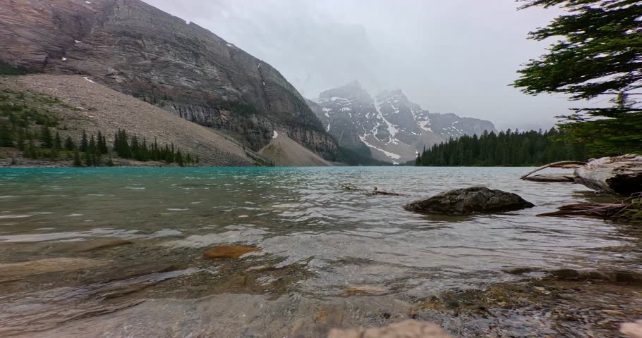 Moraine lake on a foggy and rainy summer day. Video from close to the water and the glacier covered mountains in the background.