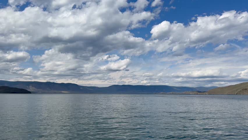 Baikal Lake on sunny summer day. Video of the Small Sea and the shores of Olkhon Island from a ferry. Beautiful blue sky with cumulus clouds over blue water. Natural background. Summer travels