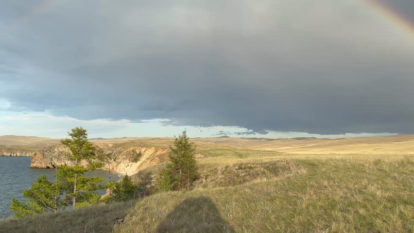 Video of a double rainbow over the shore of Baikal Lake after rain. Panoramic view of the Small Sea and the endless steppes of Olkhon Island. Natural background
