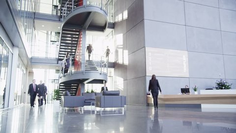 Time lapse of a large group business people moving around a spacious modern office building on a bright day.