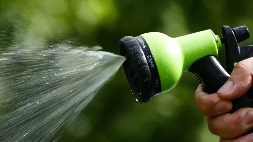 Close up on water pouring from watering can in the evening. Slow motion