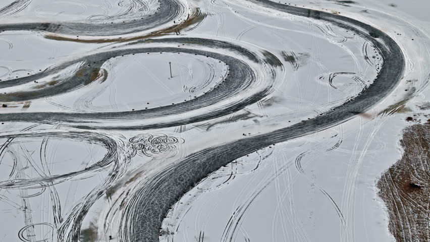 Aerial footage of a frozen race track with cars sliding around.