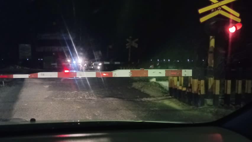 the gate at a railway crossing that has been closed is a sign that a train is passing, a night train, a queue at the ground waiting for the train to pass