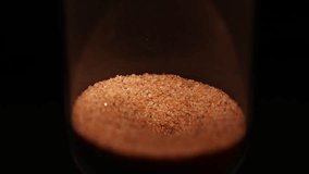 Sand in an hourglass slowly pouring out forming a vortex in the glass bulb, the relentless passage of time as an hourglass symbol. - Powered by Shutterstock - Get 15% off with code: PIKWIZARD15