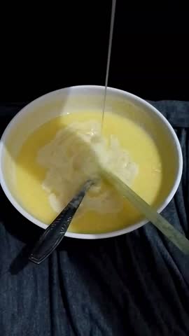 Mango, pineapple, and guava juice in a white bowl with  a spoon, pipette, and milk drops falling from above .
