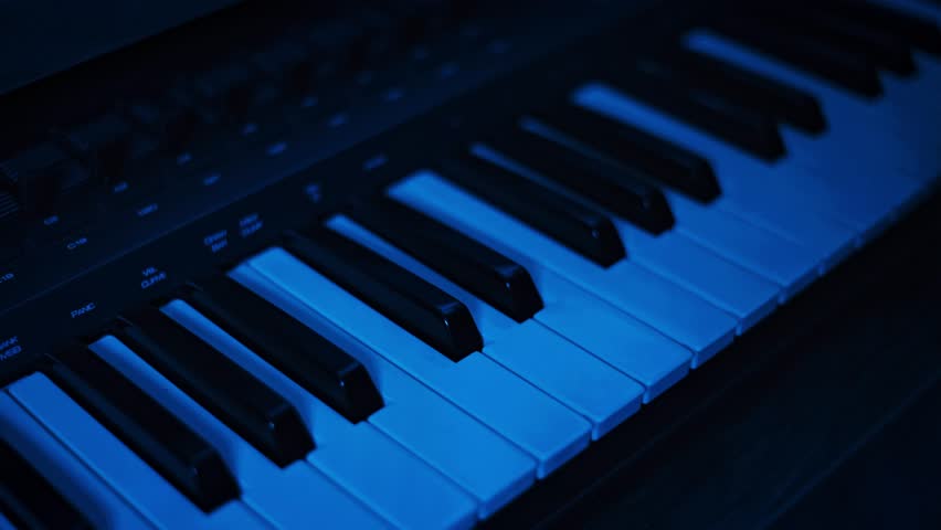 Close-up view of a single hand pressing keys on a digital synthesizer keyboard, illuminated by a mesmerizing, continuously changing sequence of vibrant RGB lights.